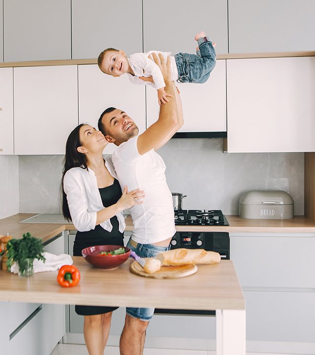 Family in a kitchen. Beautiful mother with little son. Father in a white t-shirt.